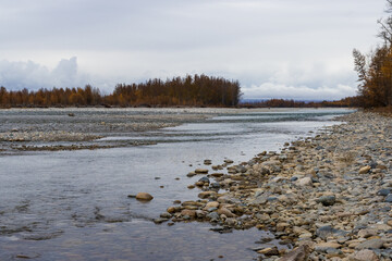 View from the shore to the river. Autumn landscape. Beautiful nature of Siberia and the Russian Far East. Travel and tourism in the Magadan region. Russia.