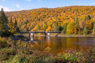 Fototapeta na wymiar A Bridge Across the River Near Jacques-Cartier National Park's Visitor's Centre Surrounded by Fall Colors, Quebec, Canada