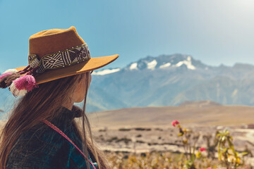Stylish hipster girl in hat walking on top of mountains. Happy young woman with backpack exploring sunny mountains. Travel and wanderlust concept. - obrazy, fototapety, plakaty