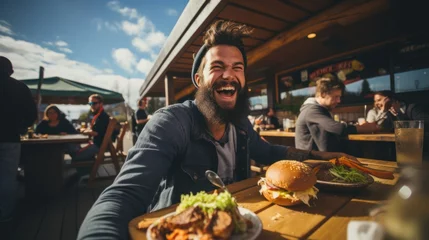Schilderijen op glas A happy man eating a burger in an outdoor restaurant as a Breakfast © sirisakboakaew