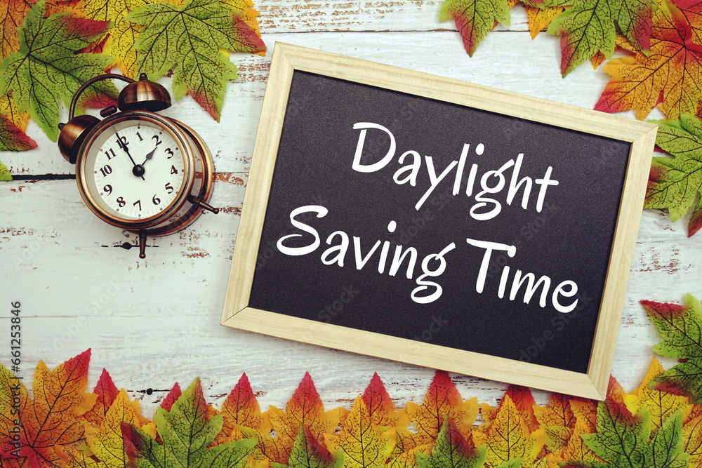 Poster daylight saving time typography text on wooden blackboard with alarm clock and maple leaves