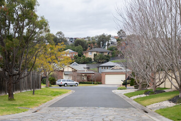 Winter view of a suburban road leads to a court, an enclosed road or cul-de-sac that typically forms a circular shape with no outlet on one end, in an Australian neighbourhood with residential houses