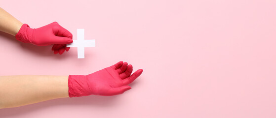 Doctor's hands with cross on pink background with space for text, top view.