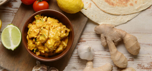 Bowl of tasty chicken tikka masala on table