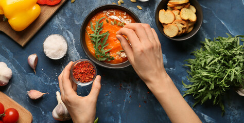 Woman seasoning tasty Indian cream soup, top view
