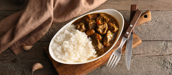 Plate with tasty curry and rice on wooden background