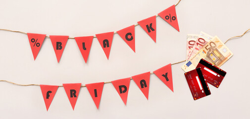Obraz premium Credit cards, money and garland with text BLACK FRIDAY on light background