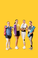 Fototapeta premium Sporty young women with equipment on yellow background