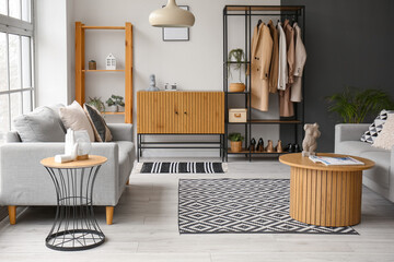 Interior of stylish living room with wooden cabinet, shelving unit and armchairs