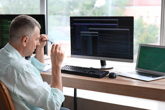 Mature male programmer working in light office