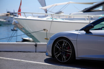 Luxury sports car on the background of yachts. - obrazy, fototapety, plakaty