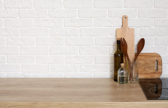 Fototapeta Wooden countertop with cutting boards and utensils near white brick wall