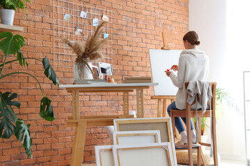 Female artist painting on easel in studio