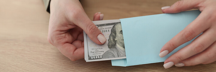 Woman takes dollar banknotes out of blue envelope at table