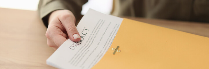 Female manager puts contract papers into yellow folder
