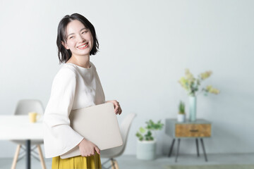 リビングやオフィスでパソコンを持つ若い女性...
