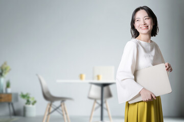 Young woman with a computer in her living room or office For bright images such as job change or...