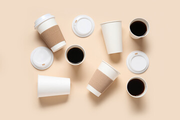 Takeaway paper cups of tasty coffee and lids on beige background