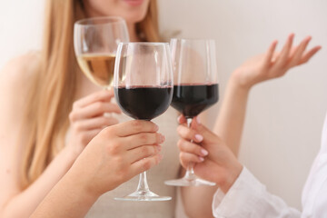 Women with glasses of exquisite red wine on light background, closeup