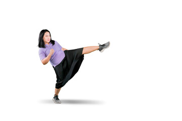 Full length portrait of an overweight woman kicking isolated on white background