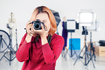 Young female photographer taking photo in studio