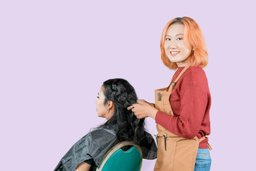 Asian hairdresser brushing her clients red hair with little comb brush and getting it ready for a cut