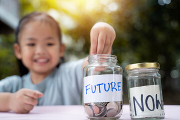 Little Asian girl saving money in Future bottle and now bottle , learning about saving, Kid save money for the future. Money, finances, insurance, and people concept. - 661279208