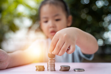 Cute asian little girl playing with coins making stacks of money , learning about saving, Kid save money for the future. Money, finances, insurance, and people concept. - 661279216