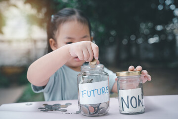 Little Asian girl saving money in Future bottle and now bottle , learning about saving, Kid save money for the future. Money, finances, insurance, and people concept. - 661279222