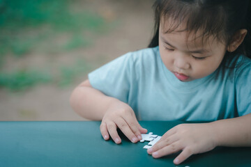 Little Asian girl doing a jigsaw puzzle. education concept. - 661279238