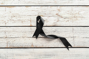 Black funeral ribbon on white wooden background