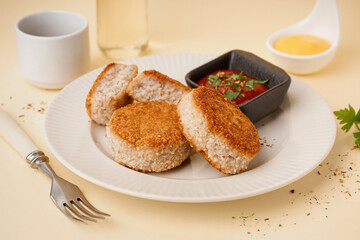 Plate with tasty meat cutlets and sauce on yellow background