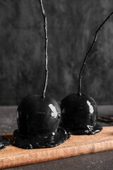 Wooden board with tasty caramel apples for Halloween on black background
