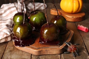 Board of tasty caramel apples for Halloween on wooden background