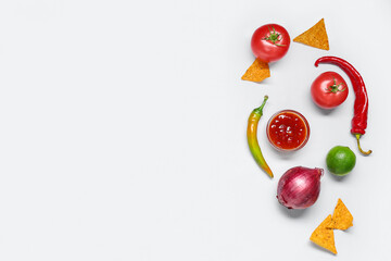 Bowl with tasty salsa sauce, nachos and ingredients on grey background