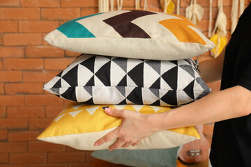 Woman holding stack of soft pillows in room