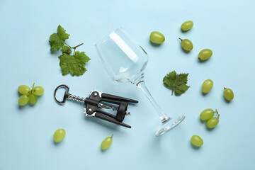 Wineglass and corkscrew on color background