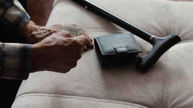 Grandfather examines the bill, next to him lies a cane and wallet. Necessary things for a pensioner.