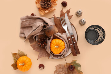 Beautiful autumn table setting with pumpkins and leaves on beige background