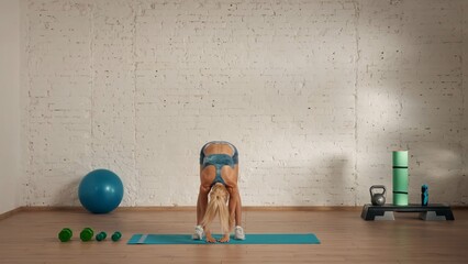Healthcare creative advertisement concept. Woman fitness coach in the room bending to the floor.