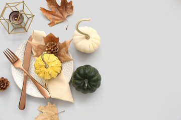 Autumn table setting with pumpkins, dried leaves and burning candle on white background