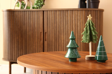 Wooden coffee table with decorative Christmas trees in living room, closeup