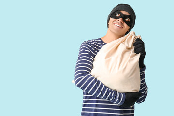 Male thief with bag on blue background