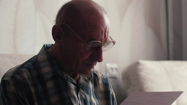 Any paper requires attention. An interested elderly man draws up documents and reads documents. Concentrated man thinking about signing an agreement.