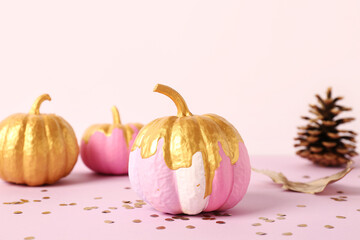 Different painted pumpkins with cone and confetti on colorful background