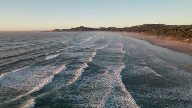 Relaxing waves along beach line at sunset, 4K drone shot