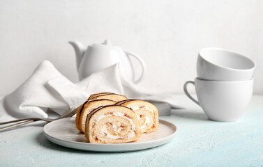 Plate with pieces of sweet sponge cake roll on white background