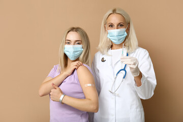 Doctor and young woman after vaccination on beige background