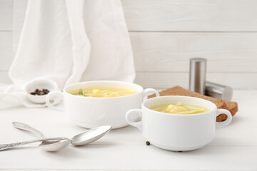 Fototapeta na wymiar Pots of tasty chicken soup on white wooden background