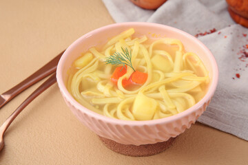 Bowl of tasty chicken soup on beige background
